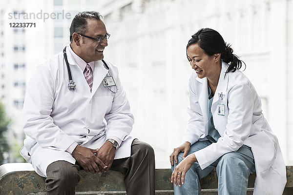 Ein spanischer Mann und eine asiatische Ärztin beraten sich über einen Fall in einem Krankenhaus.