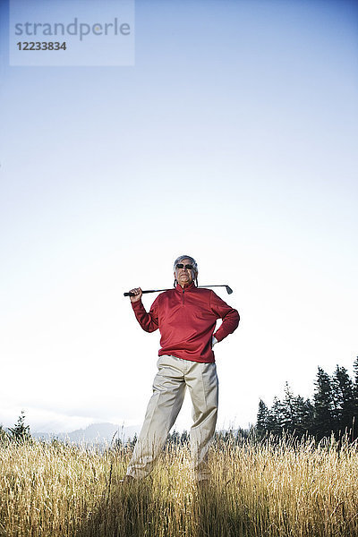 Älterer Golfer  der im schweren Rough steht und über seinen nächsten Schlag nachdenkt.