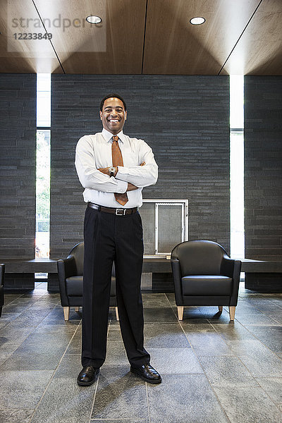 Schwarzer Geschäftsmann in der Lobby eines großen Bürogebäudes.