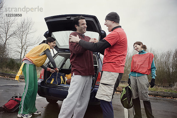 Gruppe von Freunden  die vor einem American Flag Football-Spiel Ausrüstung aus einem Auto entladen.