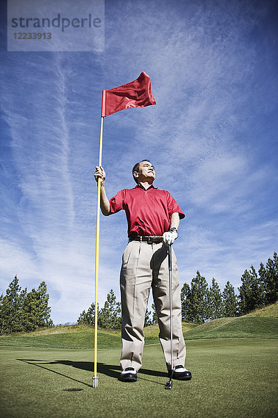 Ein älterer Golfer  der bereit ist  sich dem nächsten Schlag auf einem Golfplatz zu nähern.