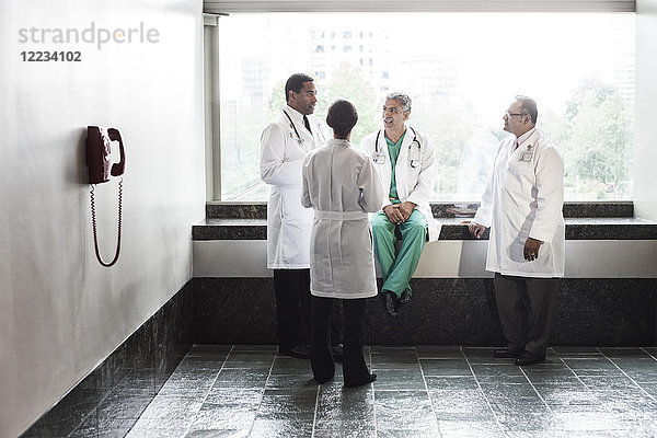 Ärzte gemischter Rasse beraten sich in einem Krankenhausflur.