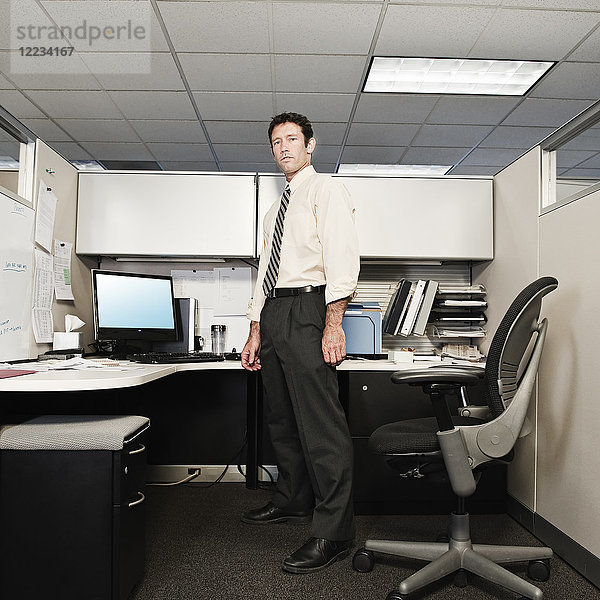 Ein junger kaukasischer Geschäftsmann in Hemd und Krawatte in seinem Büro.