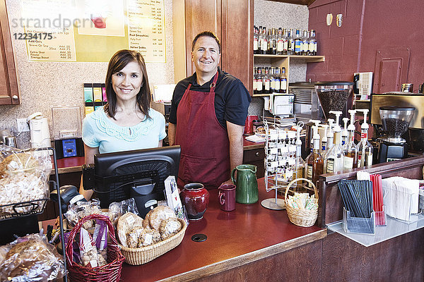 Kaukasische Frau und Mann  Geschäftsinhaber eines Cafés  an der Theke. Auslagen mit frischen Backwaren.
