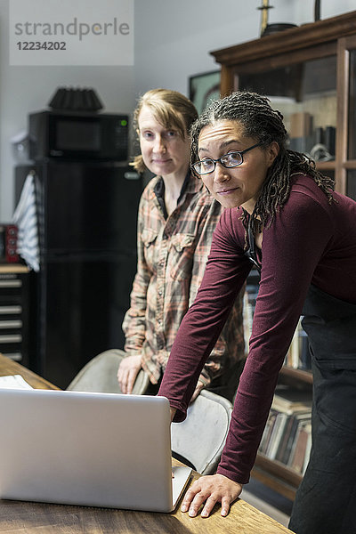 Zwei Frauen versammelten sich im Bürobereich einer Metallwerkstatt um einen Tisch und betrachteten einen Laptop.