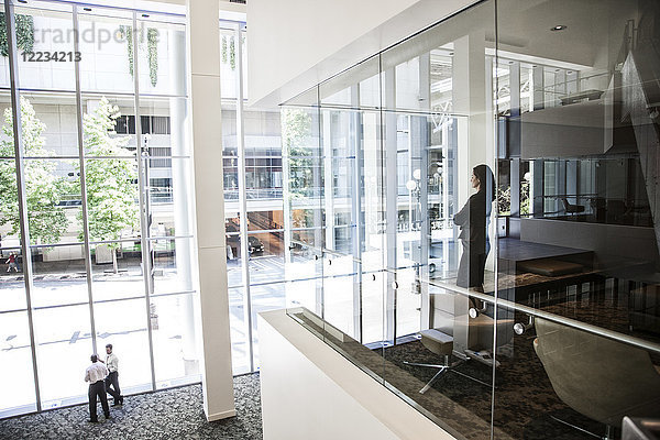 Geschäftsfrau  die am Fenster eines Konferenzraumes in einem großen Geschäftszentrum steht.