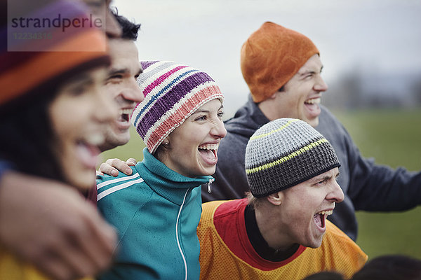 Gruppe von befreundeten Männern und Frauen  die bei einer informellen Sportveranstaltung im Winter jubeln.