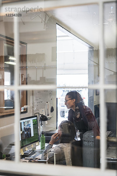 Zwei Frauen schauen auf den Computerbildschirm im Bürobereich der Metallwerkstatt.