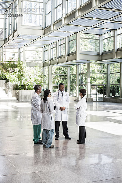 Gemischtrassige Ärztegruppe trifft sich in der Lobby eines großen Krankenhauses
