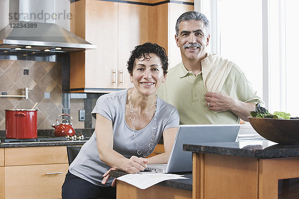 Kaukasischer Mann und Frau in einer Küche mit einem Laptop.