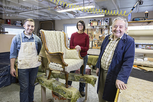 Älterer Polsterer aus dem Kaukasus und seine Zweitbesetzung aus jungen Leuten  die an einem antiken Stuhl arbeiten.