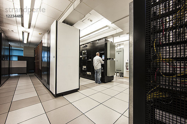 Computer-Serverraum-Racks mit Techniker im Hintergrund.