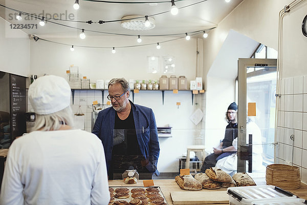 Männlicher Kunde kauft Lebensmittel vom Besitzer in der Bäckerei