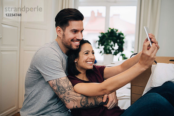 Glückliches Paar nimmt Selfie auf dem Handy  während es sich im Schlafzimmer ausruht.