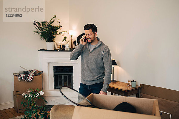 Lächelnder Mann beim Telefonieren im Wohnzimmer