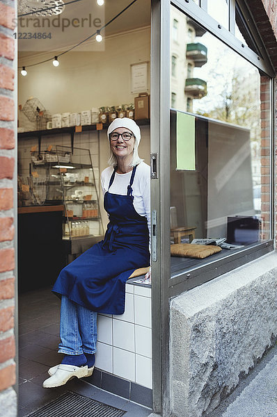 Porträt eines lächelnden Senior-Bäckers an der Kasse in der Bäckerei