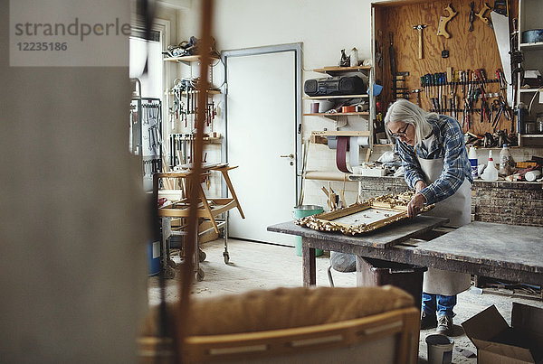 Senior Inhaberin bei der Arbeit an geschnitzten Produkten in der Werkstatt