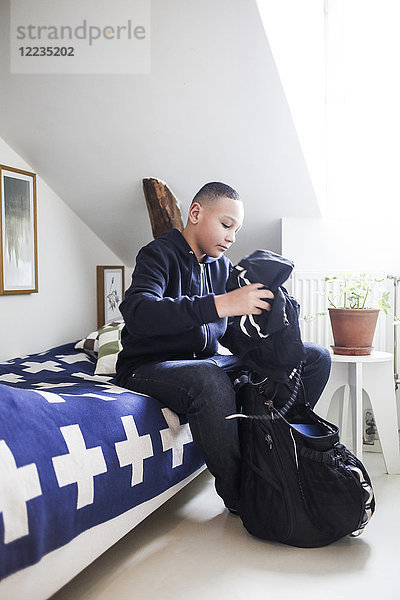 Teenager Junge packt Kleidung in den Rucksack im Schlafzimmer zu Hause