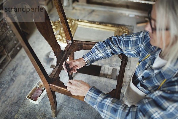 Hochwinkelansicht des Handwerkers  der in der Werkstatt Holzstühle herstellt.