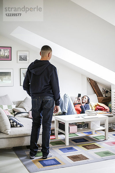 Mutter fotografiert Sohn auf dem Handy im Wohnzimmer zu Hause