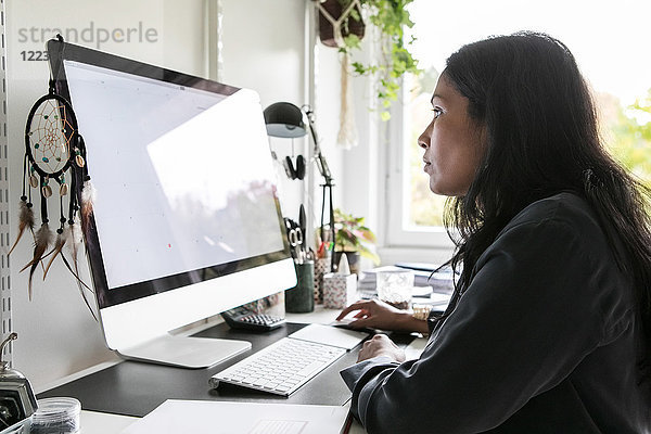 Seitenansicht der Designerin mit dem Computer im Home-Office