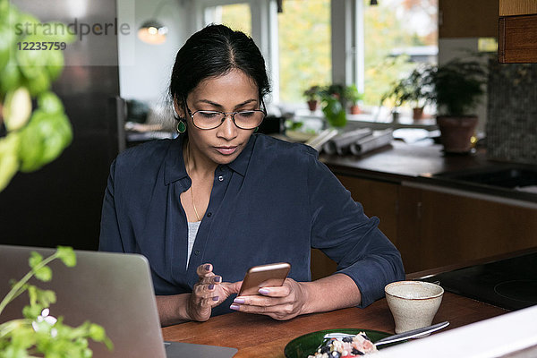 Geschäftsfrau mit Handy und Laptop auf dem Tisch im Home-Office