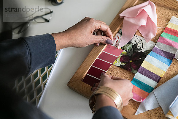 abgeschnittene Hände der Geschäftsfrau mit Farbmustern am Schreibtisch im Home-Office