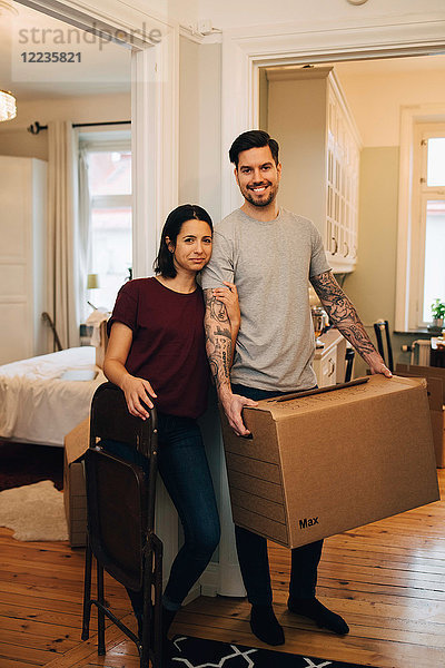 Porträt eines lächelnden Paares mit Box bei den Zimmern zu Hause