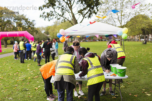 Freiwillige überprüfen Läufer beim Charity-Lauf im Park