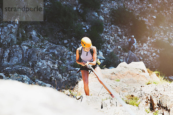Weibliche Klettererin beim Abseilen von Felsen