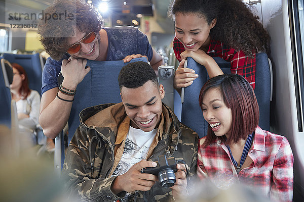 Junge Freunde beim Betrachten von Fotos auf der Digitalkamera im Personenzug
