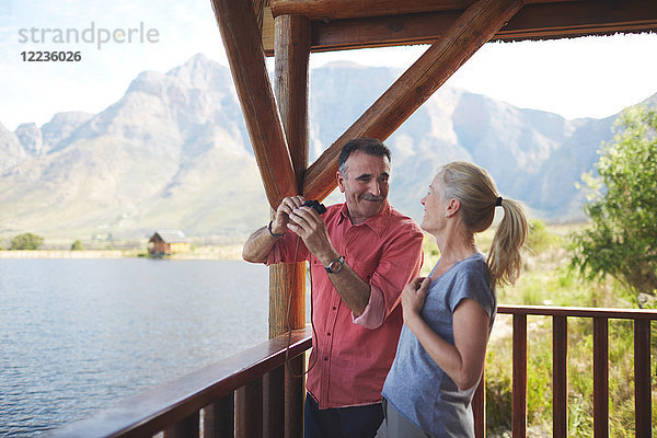 Glückliches Paar mit Fernglas mit Seeblick vom Balkon aus