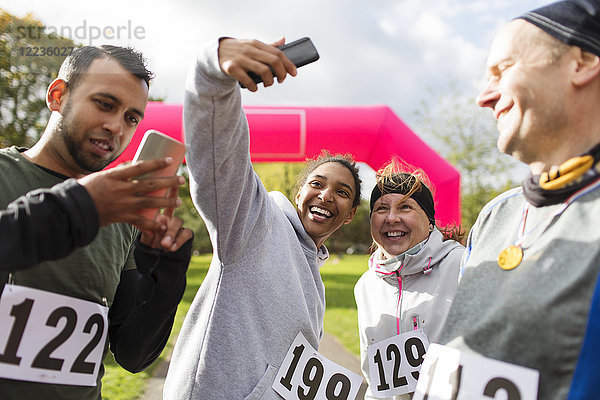 Glückliche Läuferfreunde nehmen Selfie mit Fotohandy beim Charity-Lauf im Park mit