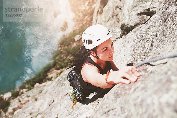 Fokussierte  zielstrebige  weibliche Klettererin beim Klettern