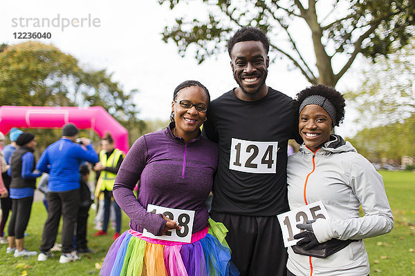 Portrait lächelnde  selbstbewusste Familie mit Marathon-Lätzchen beim Benefizlauf im Park