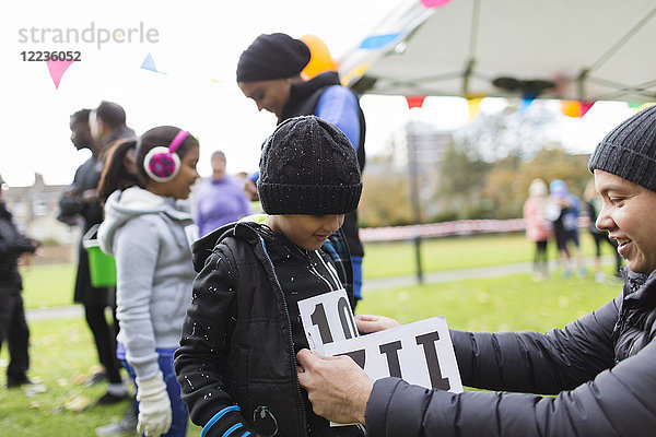 Vater pinnt Marathon-Lätzchen auf Sohn beim Benefizlauf im Park