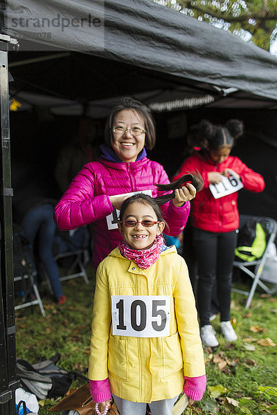 Portrait lächelnde  selbstbewusste Mutter und Tochter Läufer im Charity-Laufzelt