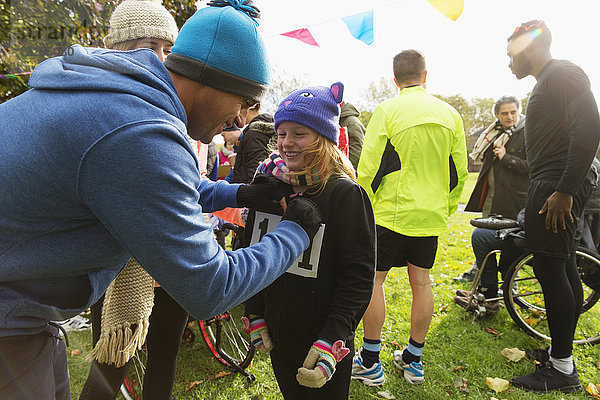 Vater pinnt Marathon-Lätzchen auf Tochter beim Benefizlauf im Park