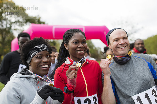 Portrait lächelnde Läufer mit Medaillen beim Benefizlauf