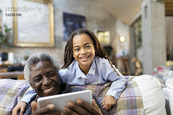 Portrait lächelnder Großvater und Enkelin mit digitalem Tablett