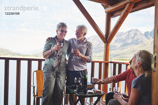 Glückliche aktive Seniorenpaare beim Weintrinken auf dem Sommerbalkon
