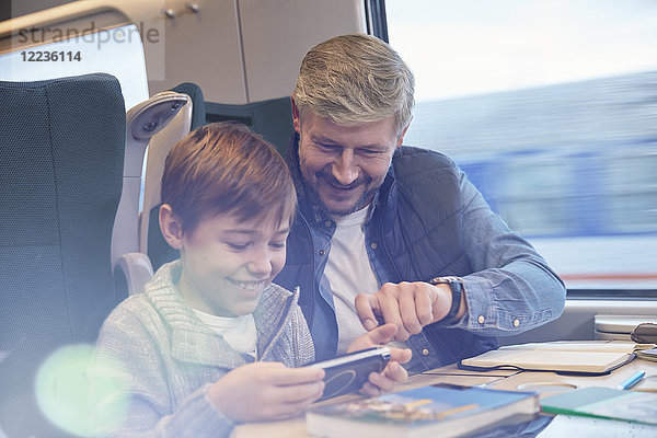 Vater und Sohn mit Smartphone im Personenzug