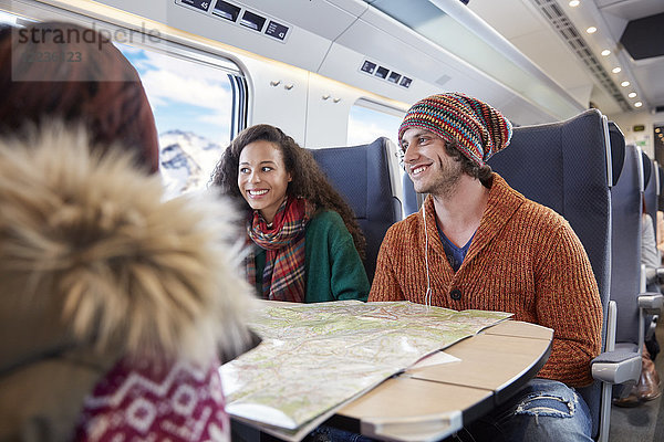 Lächelnde junge Freunde planen mit Karte im Personenzug