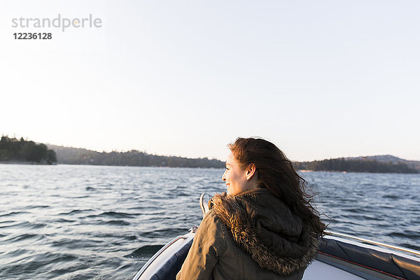Lächelnde Frau beim Bootfahren auf dem sonnigen  ruhigen See
