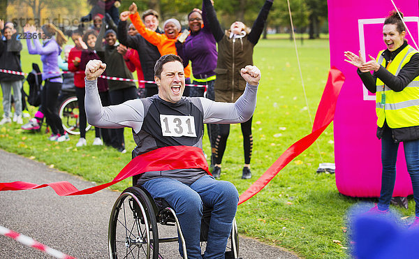 Begeisterter Mann im Rollstuhl überquert Ziellinie beim Charity-Rennen im Park