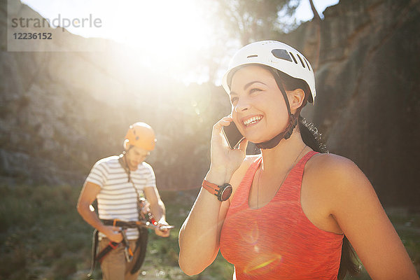 Lächelnde Klettererin im Gespräch mit dem Smartphone