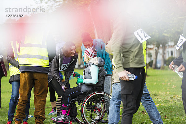 Frau im Rollstuhl im Gespräch mit Freunden beim Charity-Rennen im Park