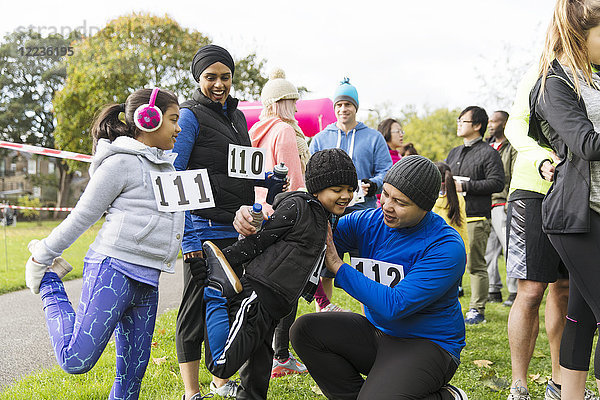 Familienläufer bereiten sich vor  strecken sich beim Benefizlauf im Park