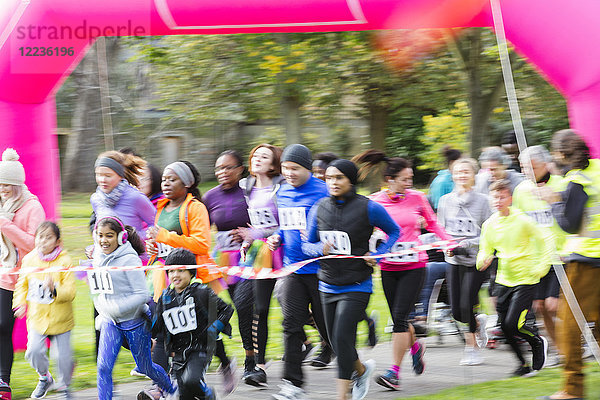 Läufer überqueren die Ziellinie beim Charity-Lauf im Park