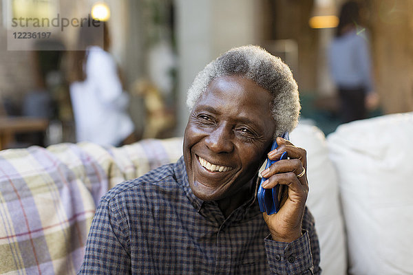 Lächelnder älterer Mann spricht auf dem Smartphone